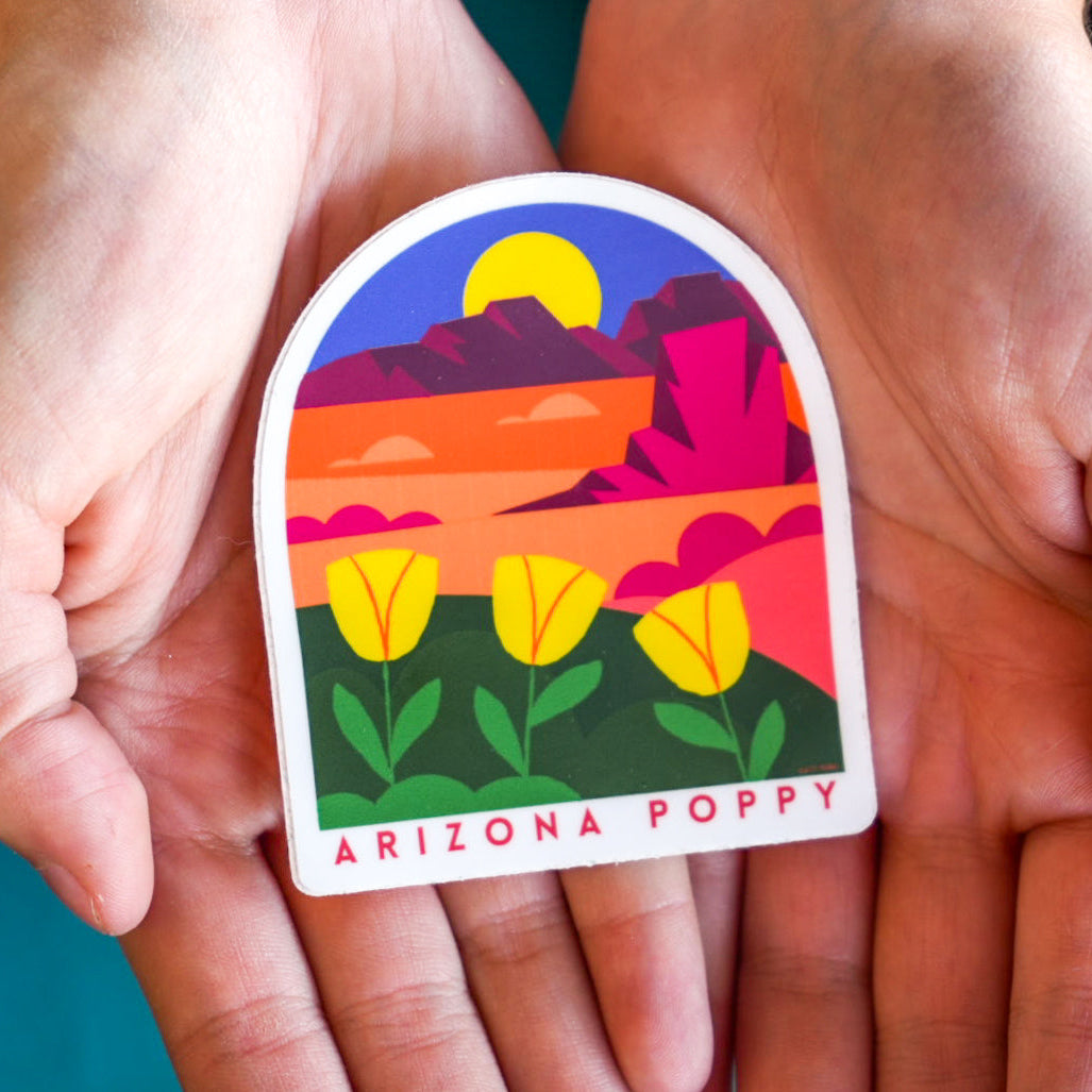 Colorful sticker of a desert landscape with flowers held between two hands against a blue background